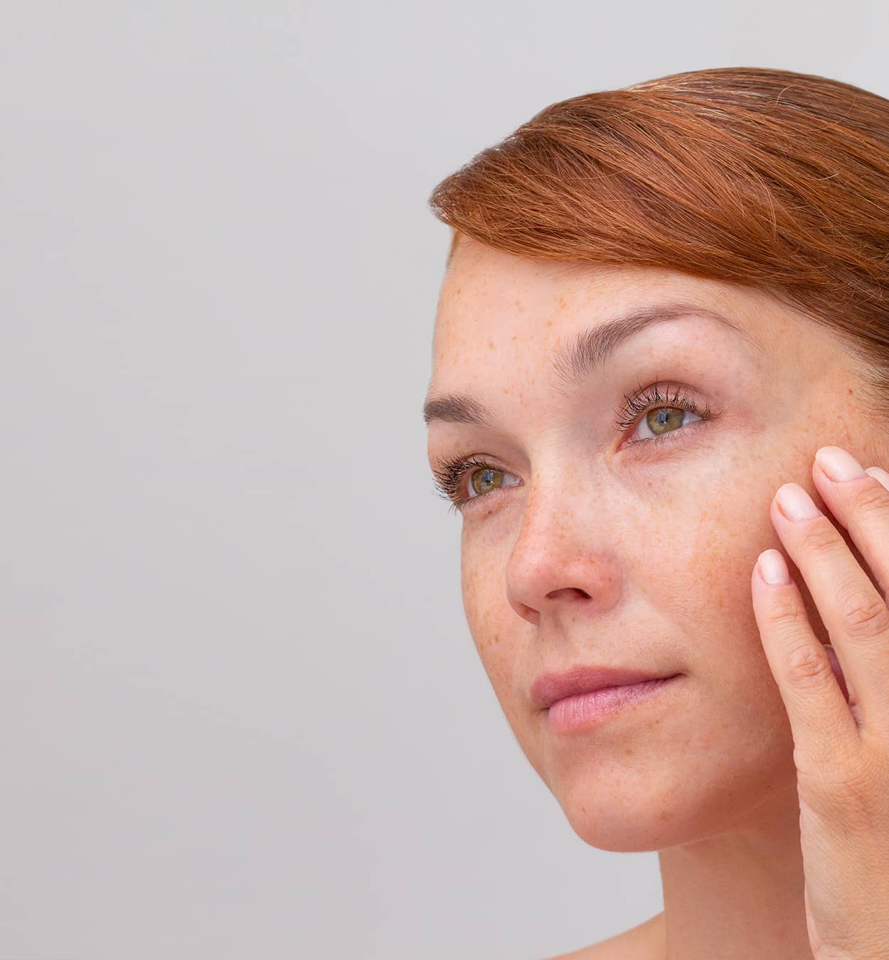 Woman looking in mirror and touching face Woman looking in mirror and touching face